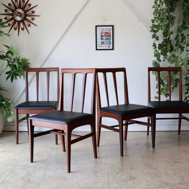 Set of four mid-century British dining chairs by A.Younger Ltd., teak wood with visible grain, black leather seats, slender.