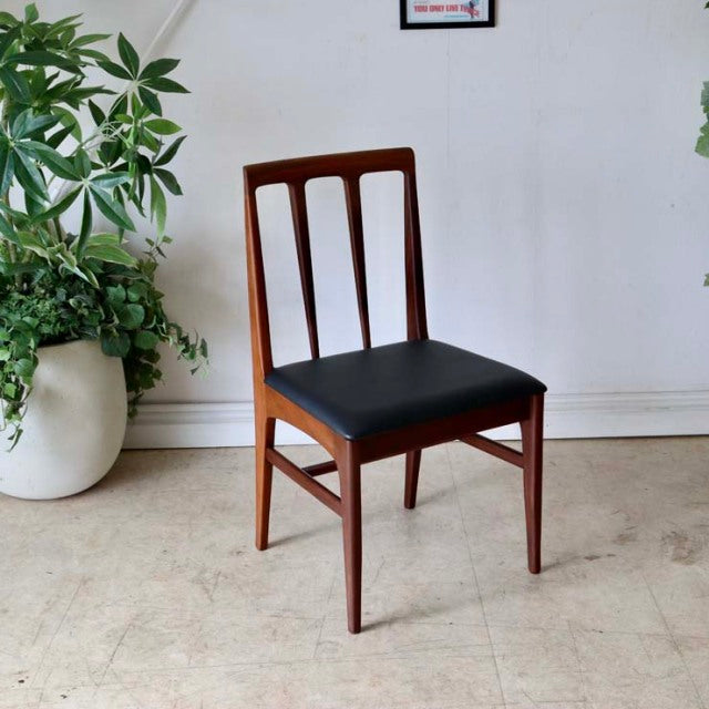 Mid-century British teak dining chair with vertical slat back and black leather seat, vintage Danish style.