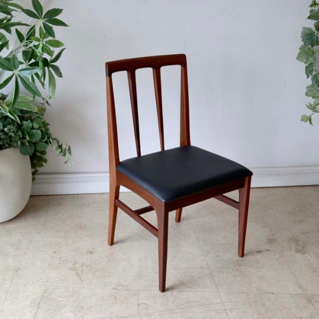 Vintage mid-century teak dining chair with British-Denmark design, black upholstered seat, clean wood grain, slender legs,.