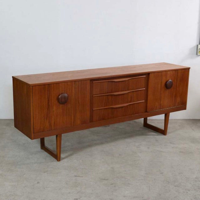 Mid-century British vintage teak sideboard with distinctive rounded wooden handles and angled legs from Denmark, showcasing.