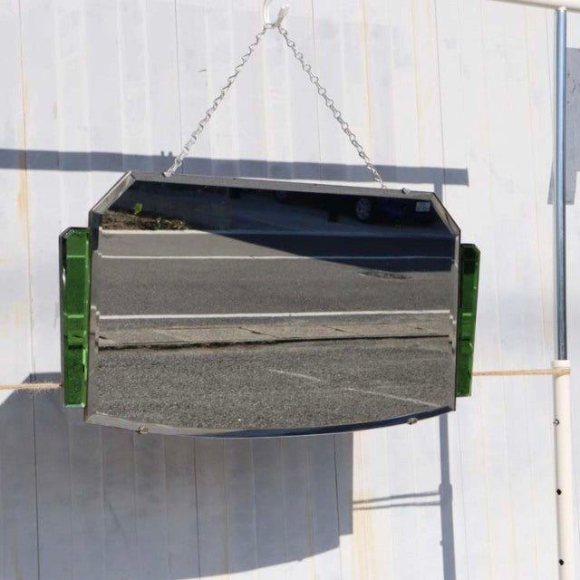 Vintage mid-century British teak wall mirror with green glass sides and distinctive beveled edges, hanging from a metal.