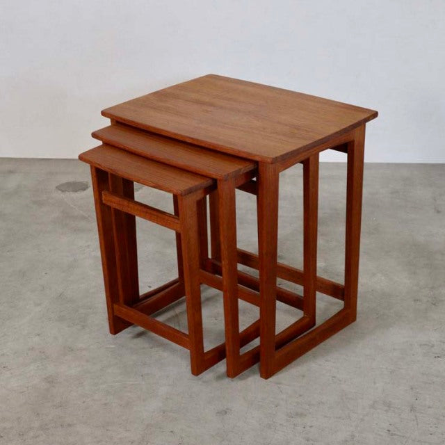 Set of three vintage mid-century teak nest tables with clean lines and visible wood grain, showcasing British-Denmark design .