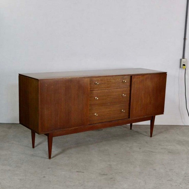 Mid-century British vintage teak sideboard with rich wood grain, tapered legs, and central drawers flanked by doors.