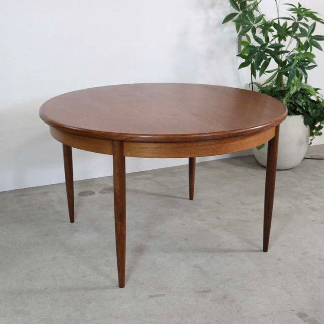 Vintage mid-century British G-Plan teak dining table with round top, visible wood grain, and tapered legs.