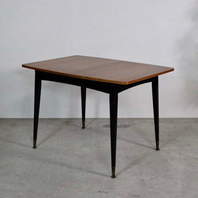 Vintage mid-century British teak dining table with rectangular top, tapered black legs, and slim brass feet accents.