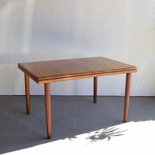 Vintage mid-century British teak dining table by WhiteANDnewton with rectangular top and tapered legs, smooth wood grain.