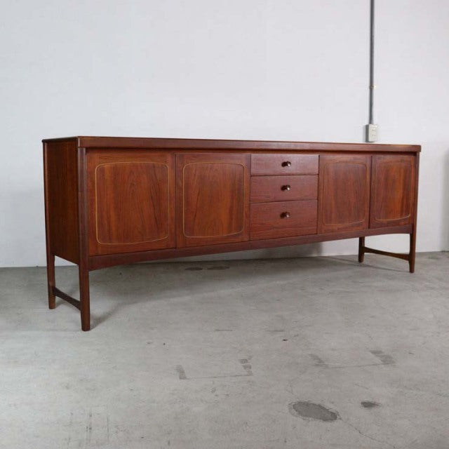 Vintage British mid-century teak sideboard by Nathan with rich wood grain, three central drawers, and four paneled doors on.