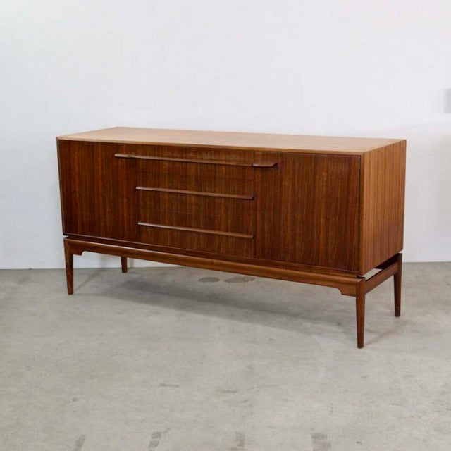 Mid-century British vintage teak sideboard by A.H.McIntosh with sleek wood grain, raised on slender legs.