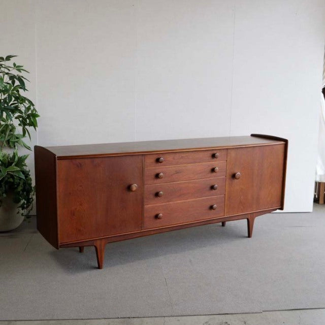 Mid-century British vintage teak sideboard by Volnay with rich wood grain, rounded edges, and tapered legs from Denmark.
