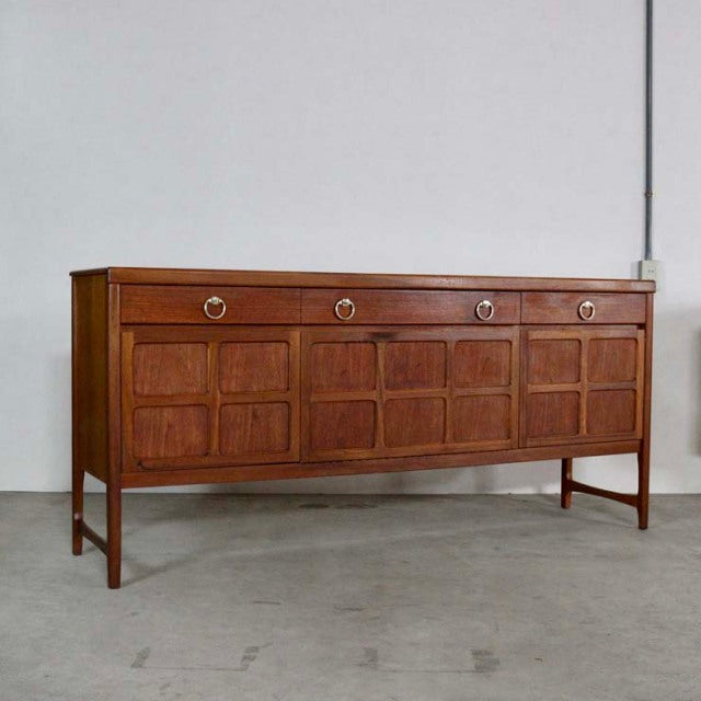 Mid-century British teak sideboard by Nathan with rich wood grain, four panelled doors, round brass handles, and slender.