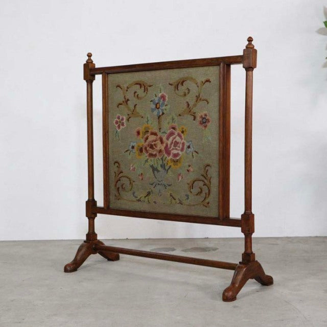 Vintage mid-century teak fire screen with British design, needlepoint floral tapestry panel, turned posts, and sturdy carved .