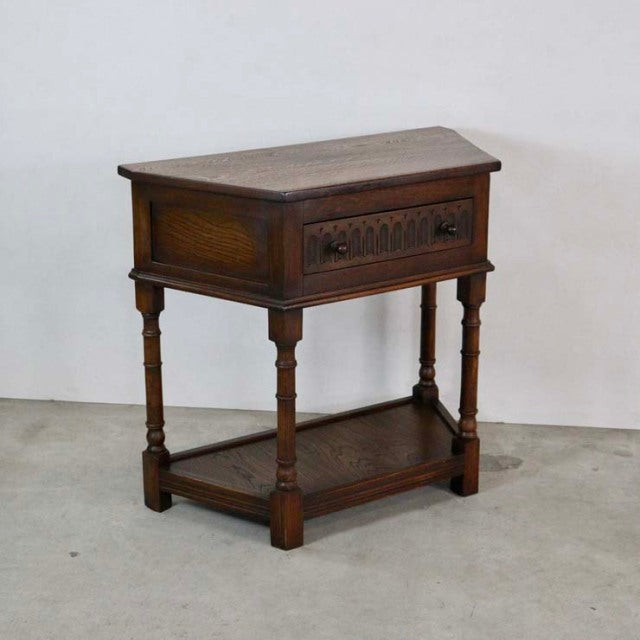 British mid-century vintage teak bedside cabinet with carved drawer front, turned legs, and lower shelf.