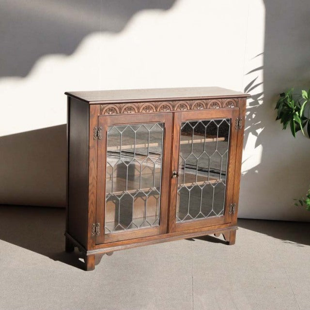 Vintage teak Jaycee British mid-century cabinet with glass paneled doors and ornate wood grain detailing.