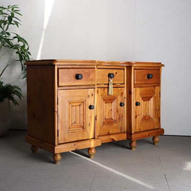 Vintage teak sideboard with British mid-century design, showcasing rich wood grain, three drawers, paneled doors, and turned .