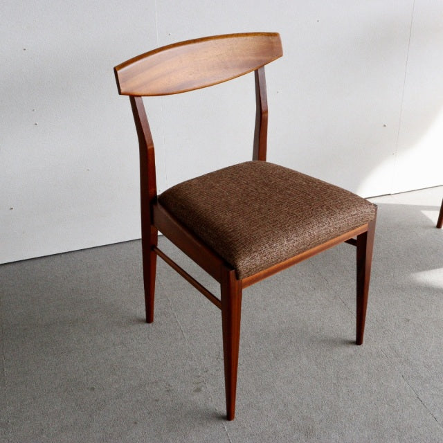 Mid-century British vintage dining chair in teak with curved backrest and brown upholstered seat.