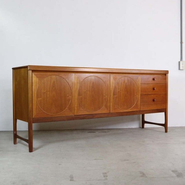 Mid-century British vintage teak sideboard by Nathan with curved panel doors, three drawers, and slender legs.