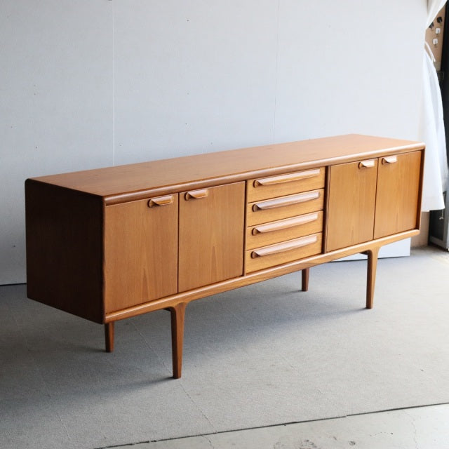 Mid-century British vintage teak sideboard by Younger with rich wood grain, four central drawers, and two cabinet doors on.