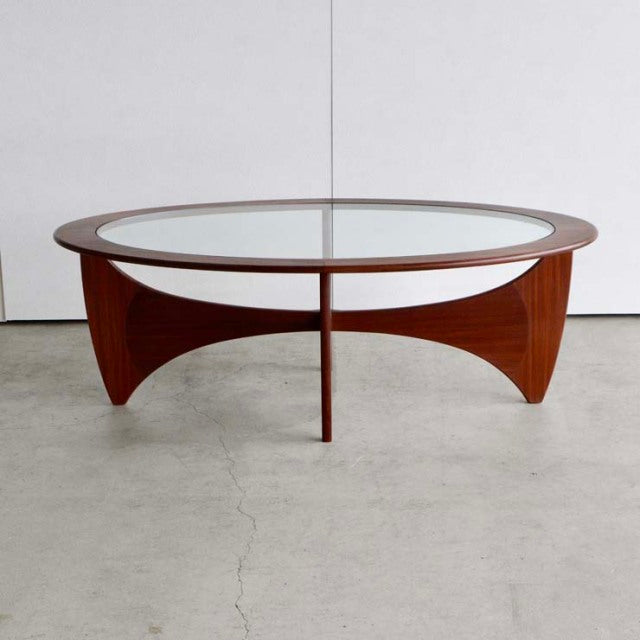 Oval mid-century British vintage G-Plan coffee table with teak curved legs and glass top, showcasing rich wood grain from.