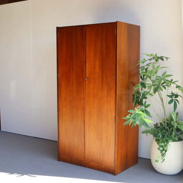 Mid-century British teak wardrobe with clean lines, rich wood grain, and tapered legs, vintage Denmark style.