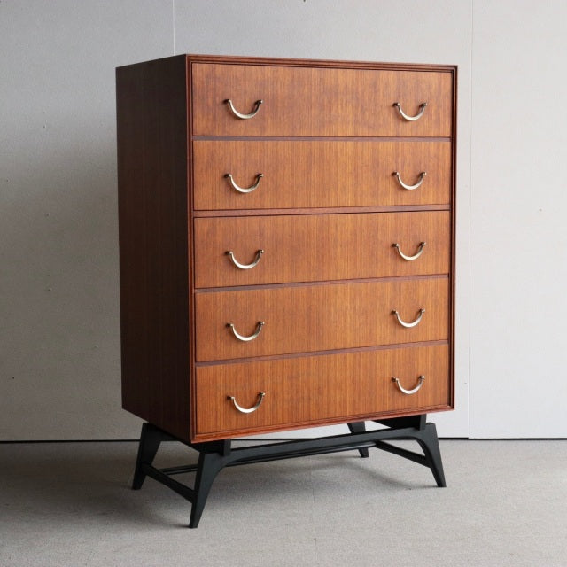 Mid-century British vintage teak chest of five drawers with curved metal handles and tapered black wooden legs from Meredew.