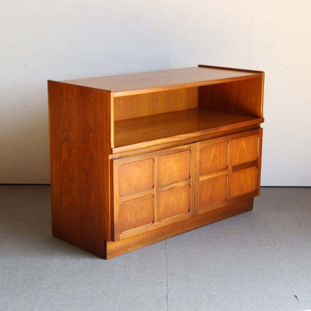 Mid-century British teak storage cabinet by Nathan with cross-design doors, rich wood grain, and clean lines.
