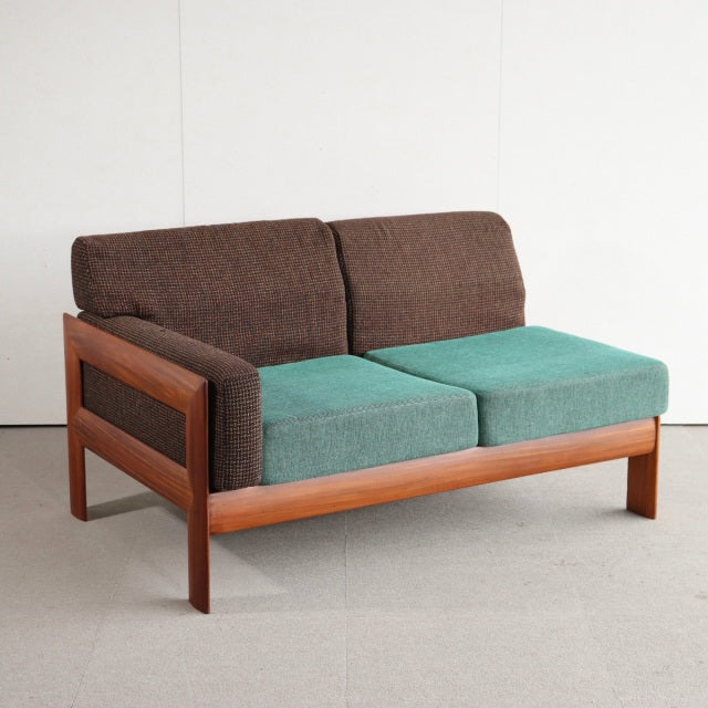 Vintage mid-century British teak two-seater sofa with Danish design, featuring brown fabric back cushions and teal.