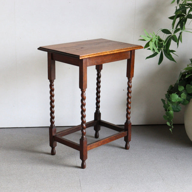Vintage British teak side table with richly grained top, twisted mid-century Denmark-style legs, and stretcher base in.
