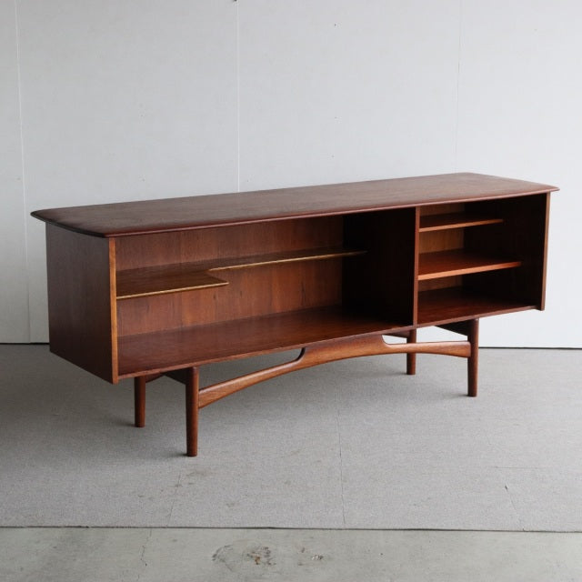 Mid-century British teak sideboard by Dalescraft with smooth wood grain, open shelving, and tapered legs from Denmark design .