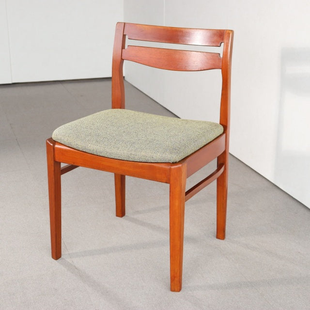 Mid-century British vintage teak dining chair with curved backrest and upholstered gray seat cushion, sleek tapered legs.