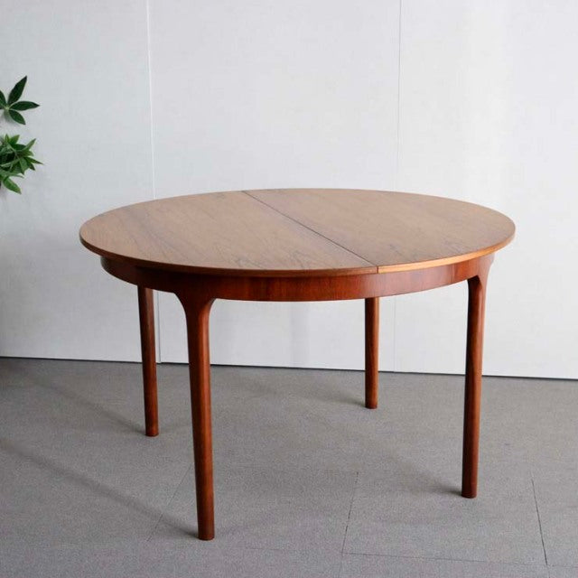 Vintage teak round dining table by McIntosh with mid-century British design, featuring tapered legs and visible wood grain,.