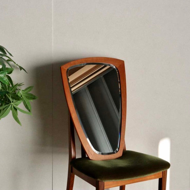 Mid-century vintage teak mirror with organic, pebble-like shape, leaning on British-style wooden chair with olive velvet.