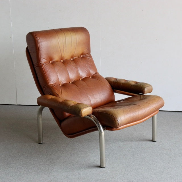 Mid-century British vintage leather lounge chair with tufted brown leather cushions, teak armrests, and polished metal legs.