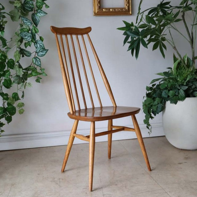 Vintage British Ercol Goldsmith high-back dining chair in natural teak with slender spindled back and angled legs,.