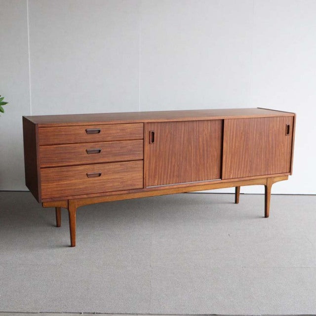 Mid-century vintage teak sideboard by Nathan, British design with sleek wood grain, tapered legs, three drawers, and sliding .
