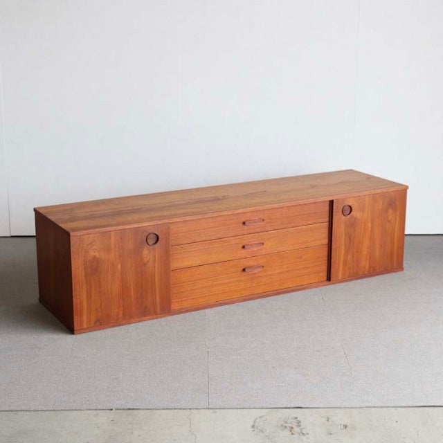 Mid-century British vintage teak sideboard by Avalon with rich wood grain, circular recessed handles, and tapered legs from.