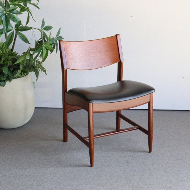 Mid-century British vintage dining chair in rich teak wood with black leather seat and gently curved backrest.