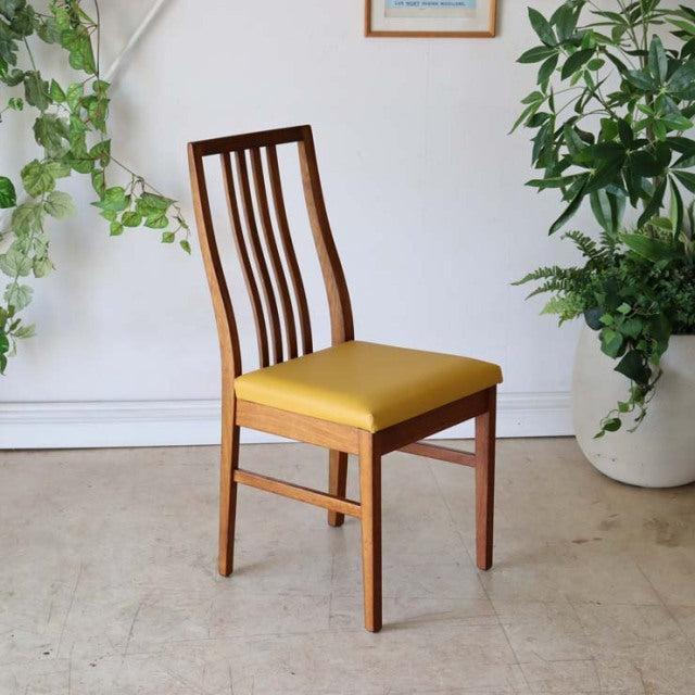 Mid-century British vintage teak dining chair with curved slatted back and mustard yellow seat cushion.