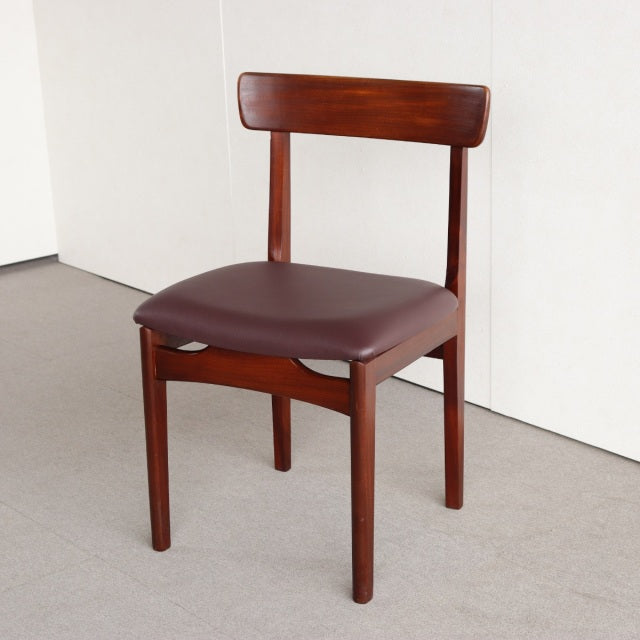 Vintage British mid-century teak dining chair with curved backrest and brown leather seat upholstery.