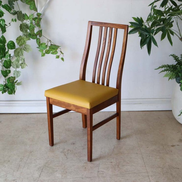 Mid-century British vintage teak dining chair with yellow upholstered seat and elegant vertical slat backrest.