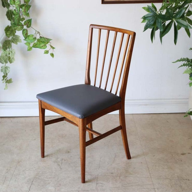Vintage teak dining chair with vertical slat back, mid-century British design, sleek tapered legs, black upholstered seat.