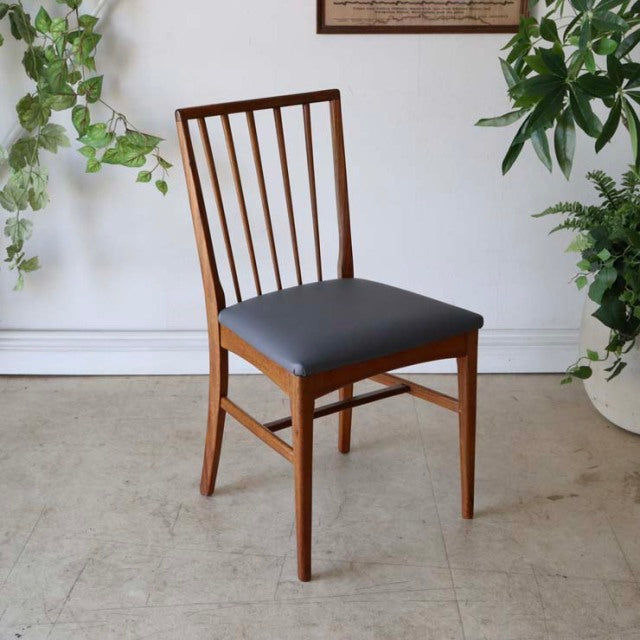 Mid-century British teak dining chair with vertical slat back and black cushioned seat, clean lines and warm wood grain.