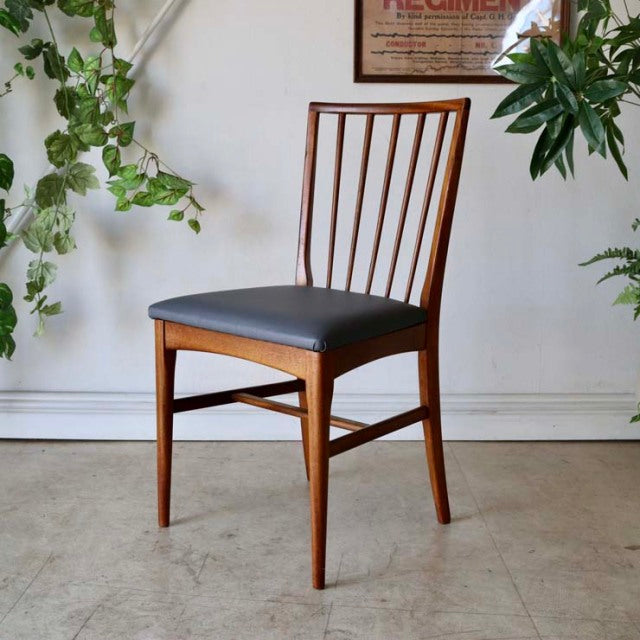 Vintage mid-century British teak dining chair with slim vertical slat back, black upholstered seat, and tapered legs, set.