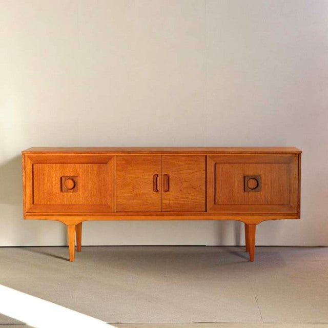 Mid-century British vintage teak sideboard with sleek wood grain, rounded corners, and tapered legs from Denmark style.