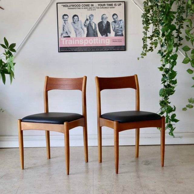 Pair of vintage mid-century teak dining chairs from Denmark with black leather seats, showcasing curved teak backrests and.