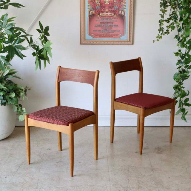 Set of two vintage teak dining chairs with mid-century British design, slim tapered legs, and maroon patterned fabric seats, .