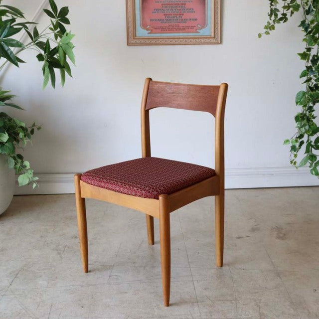 Vintage mid-century teak dining chair from Britain with clean lines, tapered legs, and floral patterned red upholstered seat.