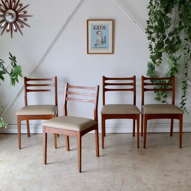 Set of four vintage teak dining chairs in mid-century British-Denmark style with ladder backs and beige upholstered seats,.
