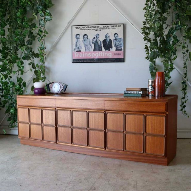 Vintage teak McIntosh sideboard with British mid-century design, featuring panelled doors and tapered legs, positioned.